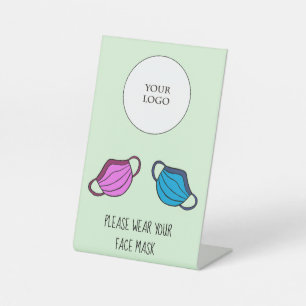 Tragen Sie bitte Ihre Gesichtsmaske mit dem Firmen Sockelschild