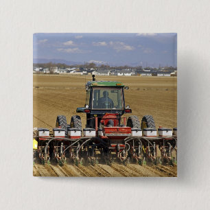 Traktor, der eine Mais-Sämaschine zieht. Button