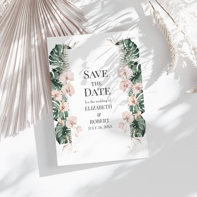 Tropischer Orchid und Monstera Save the Date Einladung (Tropical Orchid and Monstera Save the Date Invitation on a sunny white table.)