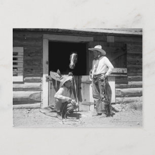 Two cowboys standing next to a barn with a horse postkarte