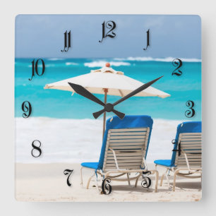 Two lounges on the ocean beach quadratische wanduhr