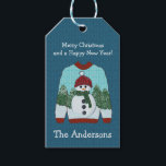 Ugly Christmas Sweater | Niedlich Snowman Geschenkanhänger<br><div class="desc">Das Design zeichnet sich durch einen wirklich niedlichen, hässlichen Pullover aus, mit einem Schneemann mit grünem Schal und einer roten Mütze auf einem schneebedeckten Kiefernwald. Blau gestrickter Wollhintergrund. Individuell gestaltbare Urlaubsnachrichten und personalisieren mit Namen oder Familienname. Karo in der Ugly Sweater Kollektion für mehr Spaß beim Dekorieren von Party, Party,...</div>