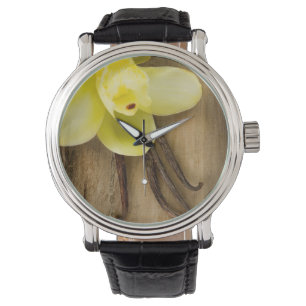 Vanille-Hülsen und Blume über hölzernem Armbanduhr