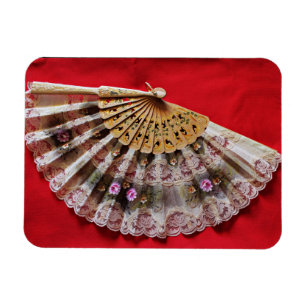 Verzierter Handheld-Lüfter auf einem roten Hinterg Magnet