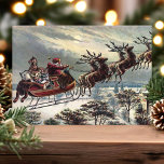 Vintag Retro Santa Claus Rentier Sleigh Feiertagskarte<br><div class="desc">Vintage Retro Santa Claus Reindeer Sleigh Holiday Card. In diesem Design führt der Weihnachtsmann seinen RentierSchlitten durch den Nachthimmel. Was für eine schöne Retro-Urlaubsszene. Personalisieren Sie dieses maßgeschneiderte Design mit Ihrem eigenen Innen-Gruß.</div>