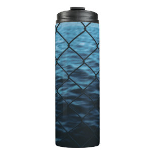 Wasserkörper vor dem Zaun der Kette Thermosbecher