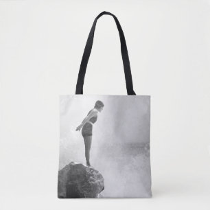 Weibliche Schwimmerin auf Felsen über dem abstürze