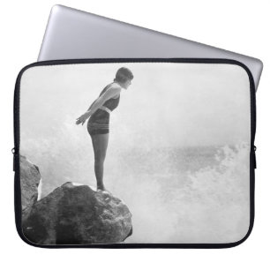 Weibliche Schwimmerin auf Felsen über tosenden Wel Laptopschutzhülle