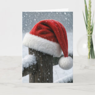 Weihnachtsmannmütze auf einem schneebedeckten Zaun Karte