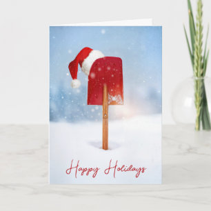 Weihnachtsmannmütze auf roter Schneeschaufel in ti Karte