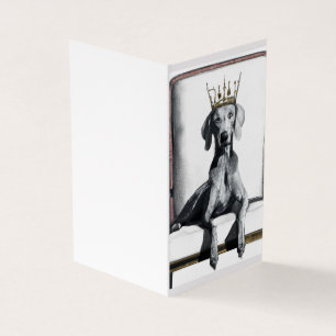 Weimaraner mit einer Krone auf einem Stuhl sitzend