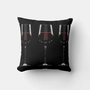 Weingläser mit Rotwein auf schwarz Kissen