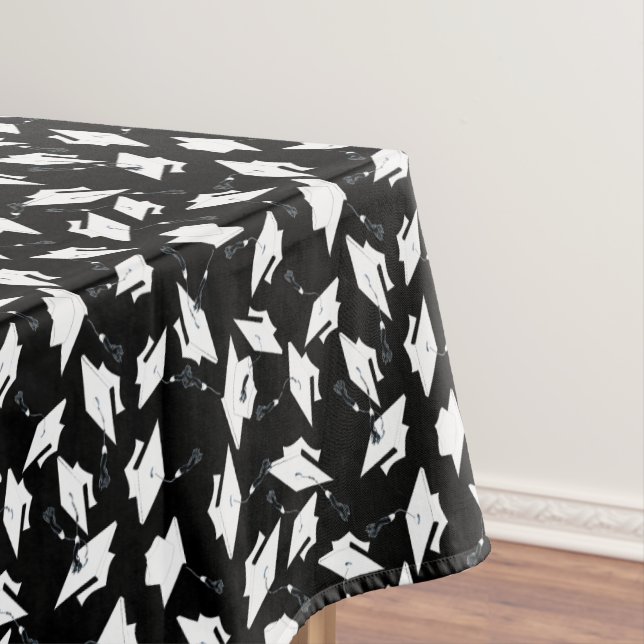 Weiße Graduierungskappen in die Luft geworfen auf  Tischdecke (Beispiel)