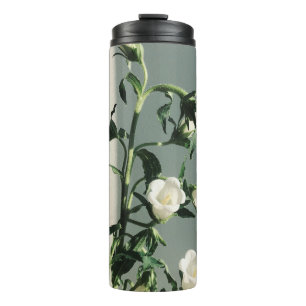 WEISSE UND GELBE BLUMEN AN DER WEISSEN WAND THERMOSBECHER