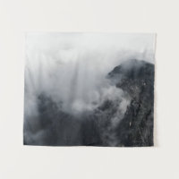 Weiße Wolken über den dunklen felsigen Bergen