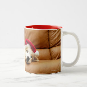 Welpe trägt einen Weihnachtshut und das Lügen au Zweifarbige Tasse