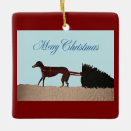 Windhund zieht einen Weihnachtsbaum durch den Schn Keramikornament