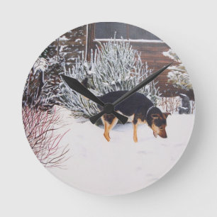 Winter snow scene with cute black and tan dog runde wanduhr