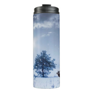 Winterlandschaft in blauer Farbe. Einsamer Baum un Thermosbecher