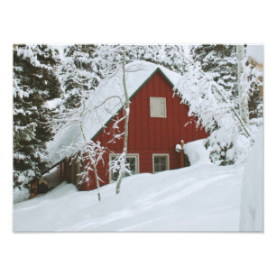 Winterliches tief verschneites rotes Haus im Wald Fotodruck