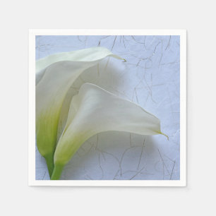 Zwei Calla liegen auf texturiertem Papier Serviette