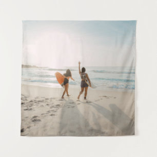 Zwei Frauen, die zum Ozean laufen und surfen Wandteppich