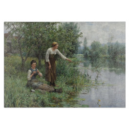 Zwei Frauen fischen auf dem Gras am Fluss Schneidebrett