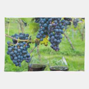 Zwei Hände, die mit Rotwein nahe blauen Trauben Geschirrtuch