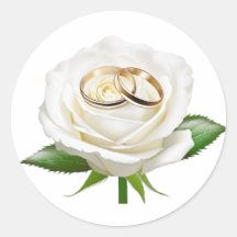 Zwei Hochzeitsringe auf einer weißen Rose